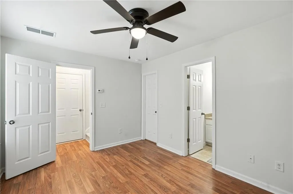 Unfurnished bedroom featuring light wood finished floors, connected bathroom, and a ceiling fan