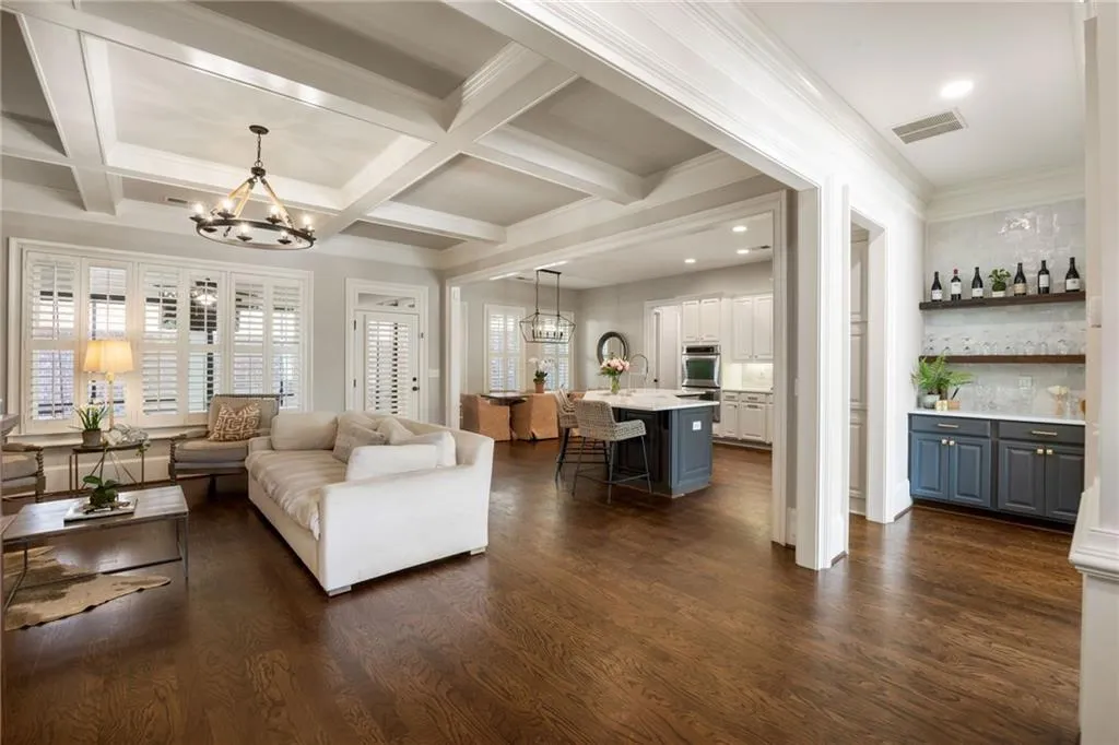 Spacious living area featuring coffered ceilings, wood-finish flooring, and white plantation shutters