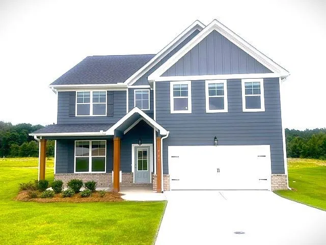 Two-story residence featuring a covered front entry with wood columns, a two-car garage, and a brick veneer foundation
