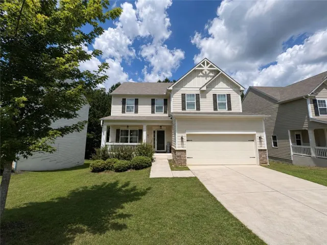 Two-story residence featuring light-toned siding, a covered front porch, and a two-car garage