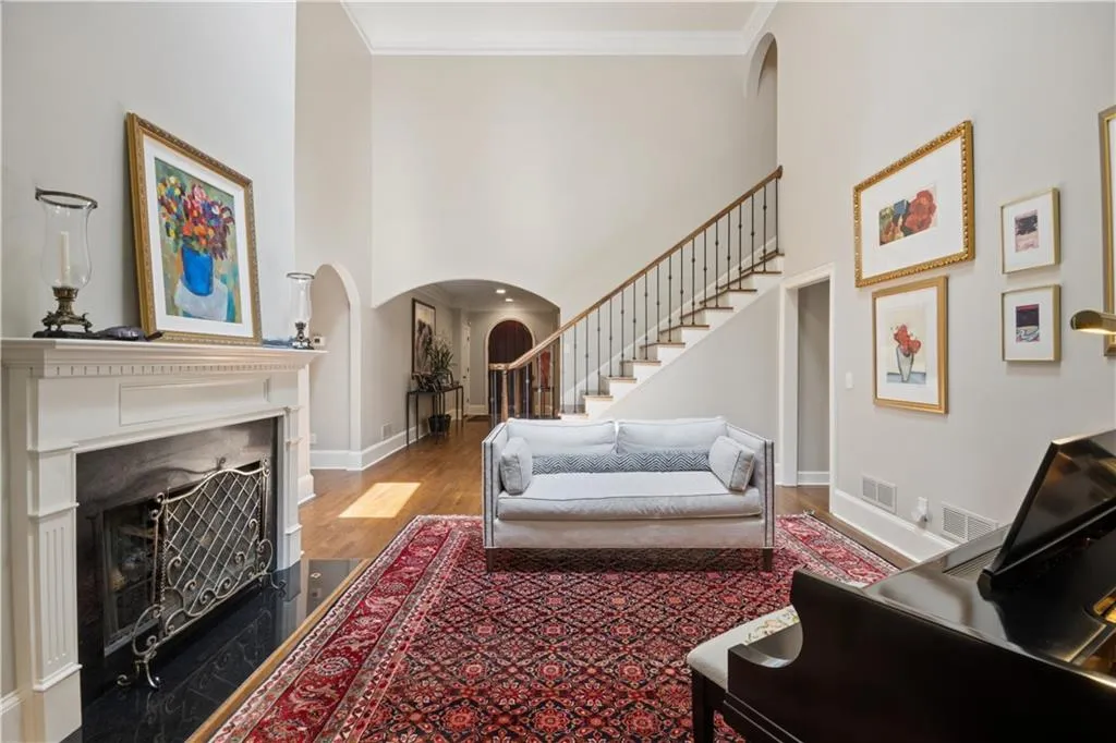 Two-story living area featuring a prominent fireplace with a white mantel and dark hearth