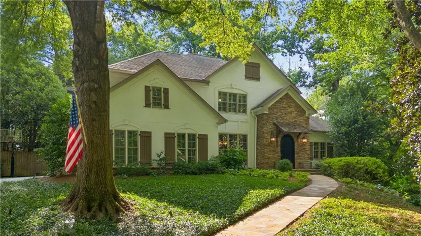 Stone and stucco exterior featuring multiple gables, dark shutters, and a stone walkway