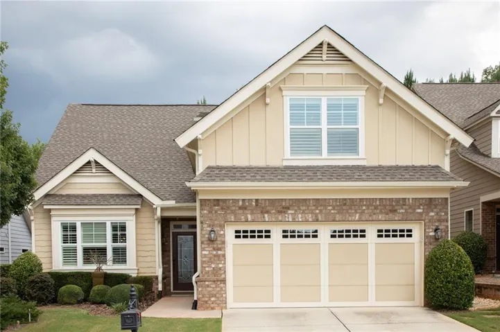 Craftsman house featuring board and batten siding, brick siding, driveway, and roof with shingles