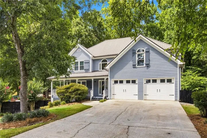 Two-story residence featuring light blue siding, a metal roof, and a two-car garage with white doors