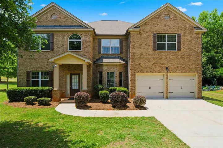 Brick exterior with architectural gables, covered entry, arched window, and attached two-car garage