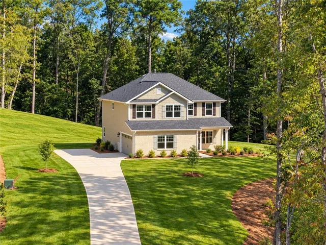Two-story Colonial home featuring a cream exterior with dark architectural shingles, multi-pane double-hung windows, and a welcoming covered entry