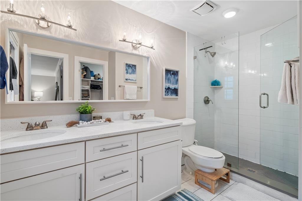 Primary bathroom featuring walk in shower, oversized vanity, toilet, tile floors, and double sink