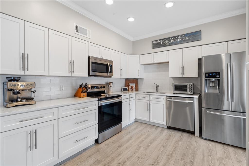 Kitchen showing sink, appliances with stainless steel finishes, and backsplash