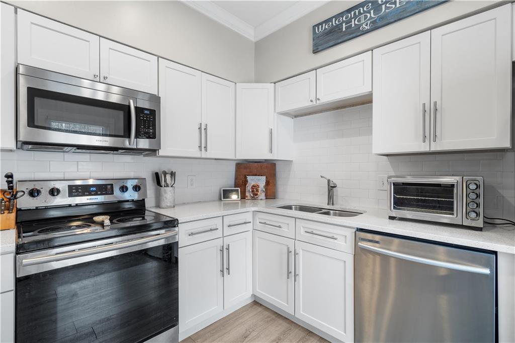 Kitchen with white cabinets, appliances with stainless steel finishes, sink, and backsplash