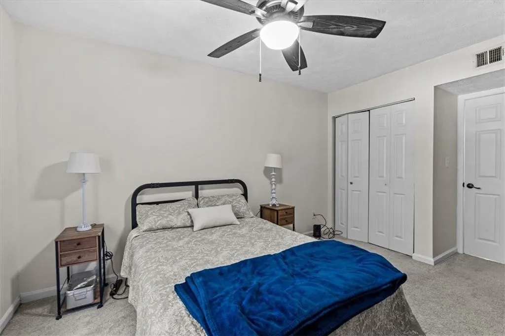 Bedroom featuring light carpet, ceiling fan, and a closet