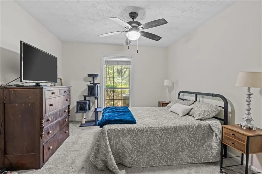 Bedroom featuring light colored carpet, ceiling fan, and a textured ceiling