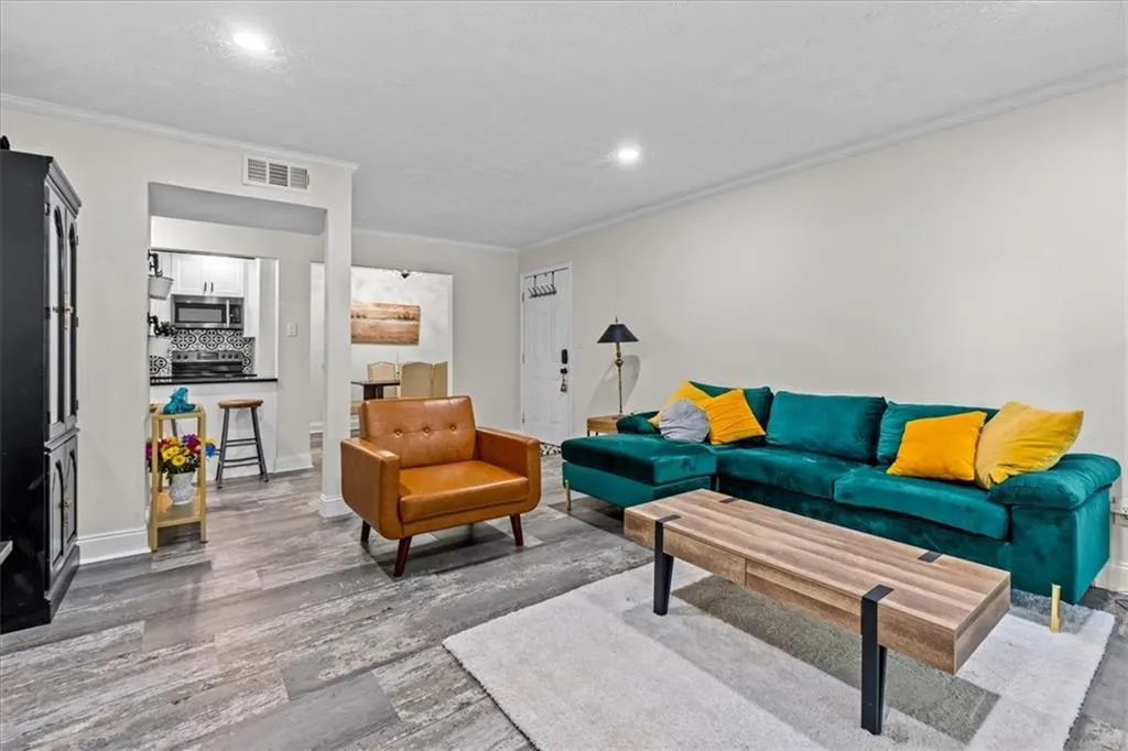 Living room with crown molding, wood finished floors, and recessed lighting