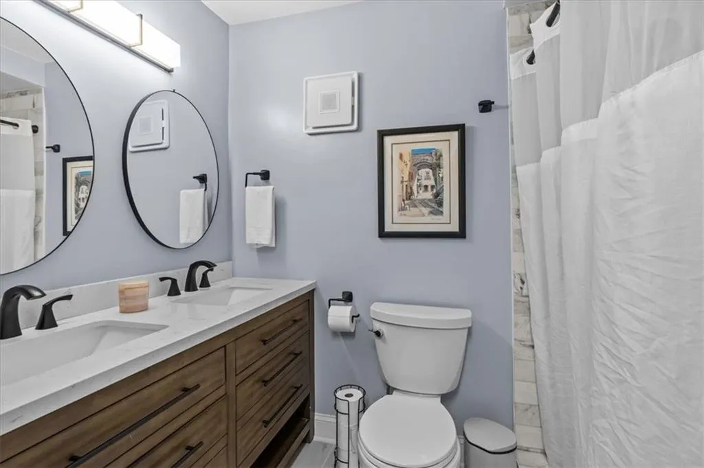 Full bath featuring double vanity and a shower with curtain