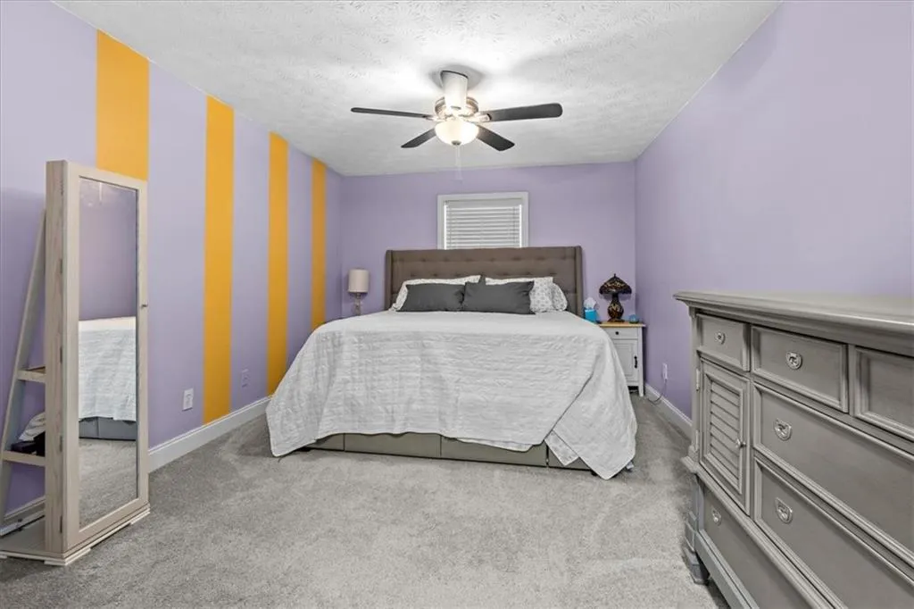 Bedroom featuring light colored carpet, a ceiling fan, and a textured ceiling