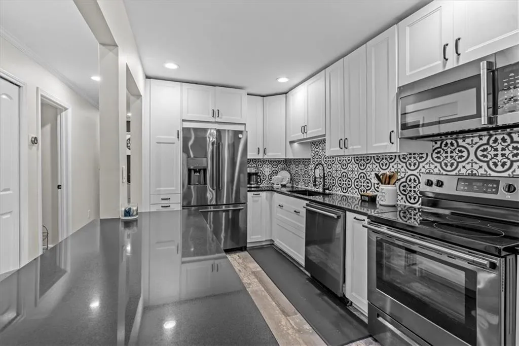 Kitchen featuring stainless steel appliances, tasteful backsplash, white cabinets, recessed lighting, and ornamental molding