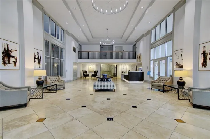Two-story foyer featuring a tile floor, a circular chandelier, and a second-level balcony with a black railing