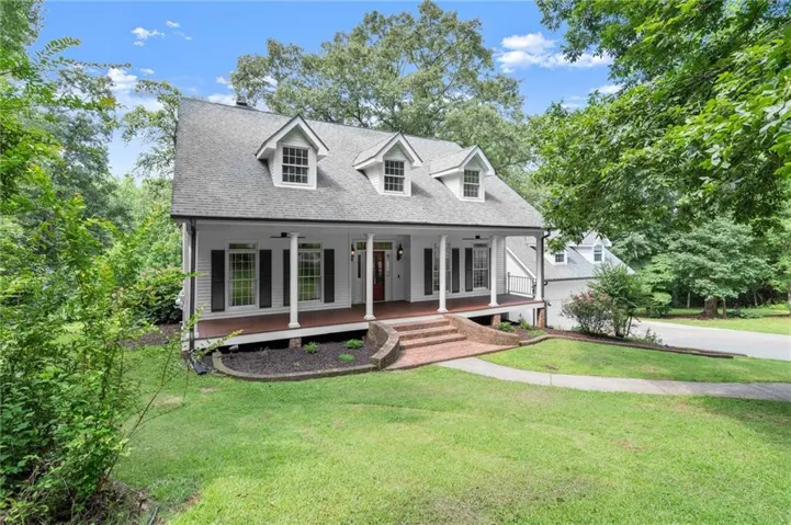 Traditional exterior with white siding and dark shutters, featuring a grey shingled roof and three dormer windows