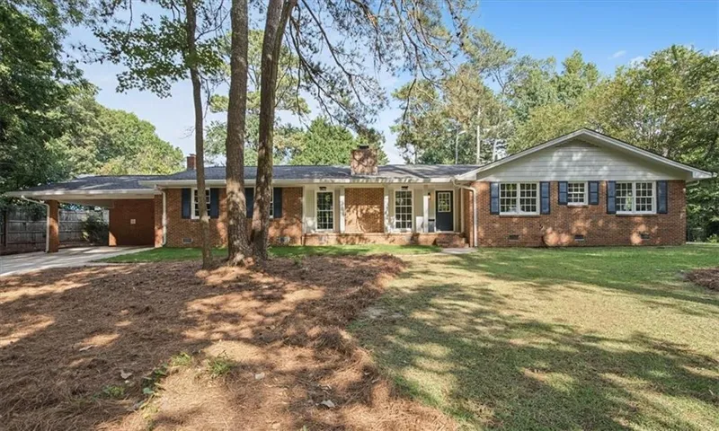 Brick exterior with a covered carport, front porch, and mature trees