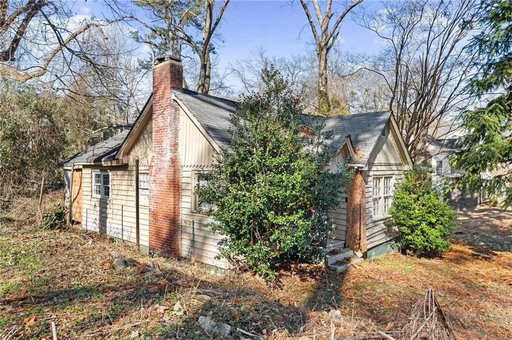 View of property exterior featuring a chimney and roof with shingles