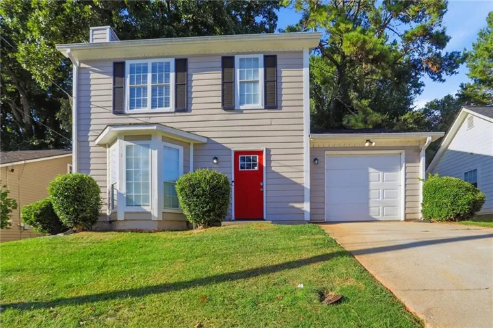 Two-story exterior with light-colored siding, a red front door, bay window, and attached single-car garage