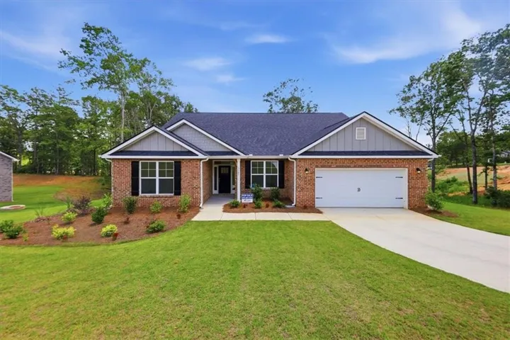 Brick exterior with gray siding accents, a dark shingle roof, a two-car garage, and a concrete driveway
