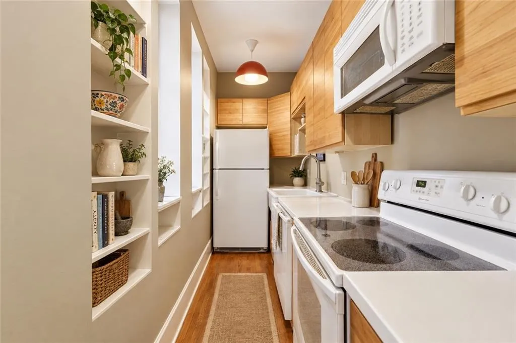 Wall cut outs, flanked by built-in shelving, draw in natural light and conversation. A step easy kitchen. Staging digitally edited.