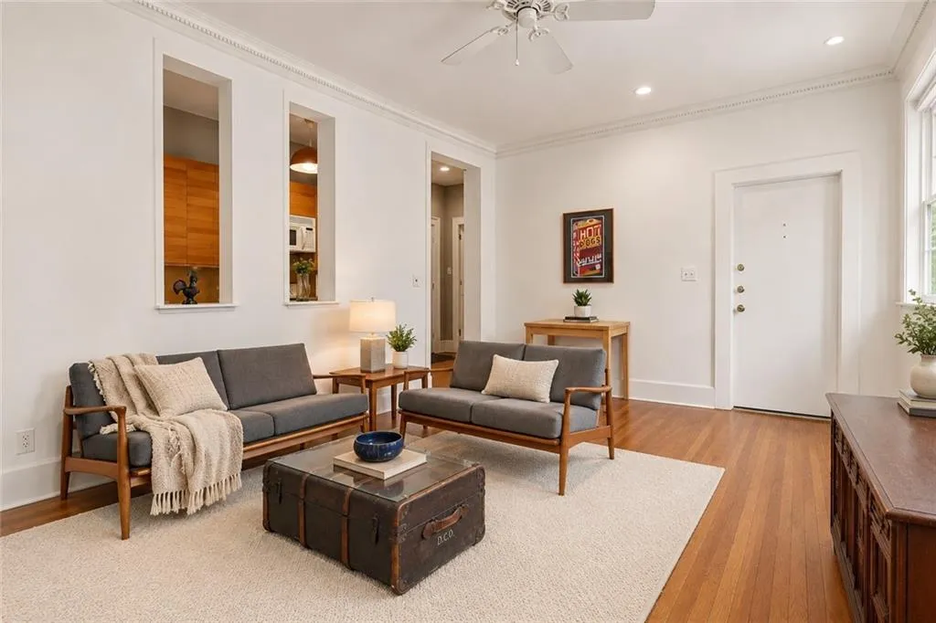 Features Hardwood flooring, recessed lighting, crown molding, ceiling fan, and decorative wall cutouts. Staging digitally edited.