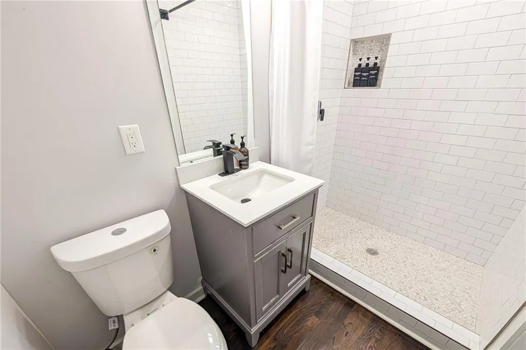 Bathroom with a shower stall, dark wood-style flooring, and vanity