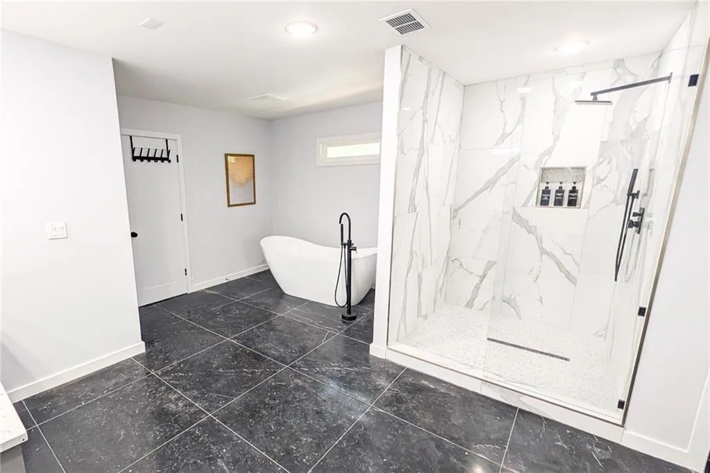 Full bath with a marble finish shower and a soaking tub