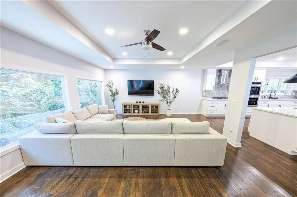 Living area featuring dark wood-style floors, a raised ceiling, ceiling fan, and recessed lighting