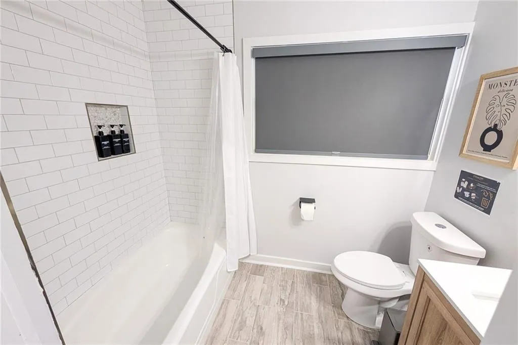 Bathroom with shower / tub combo with curtain, vanity, and wood finish floors