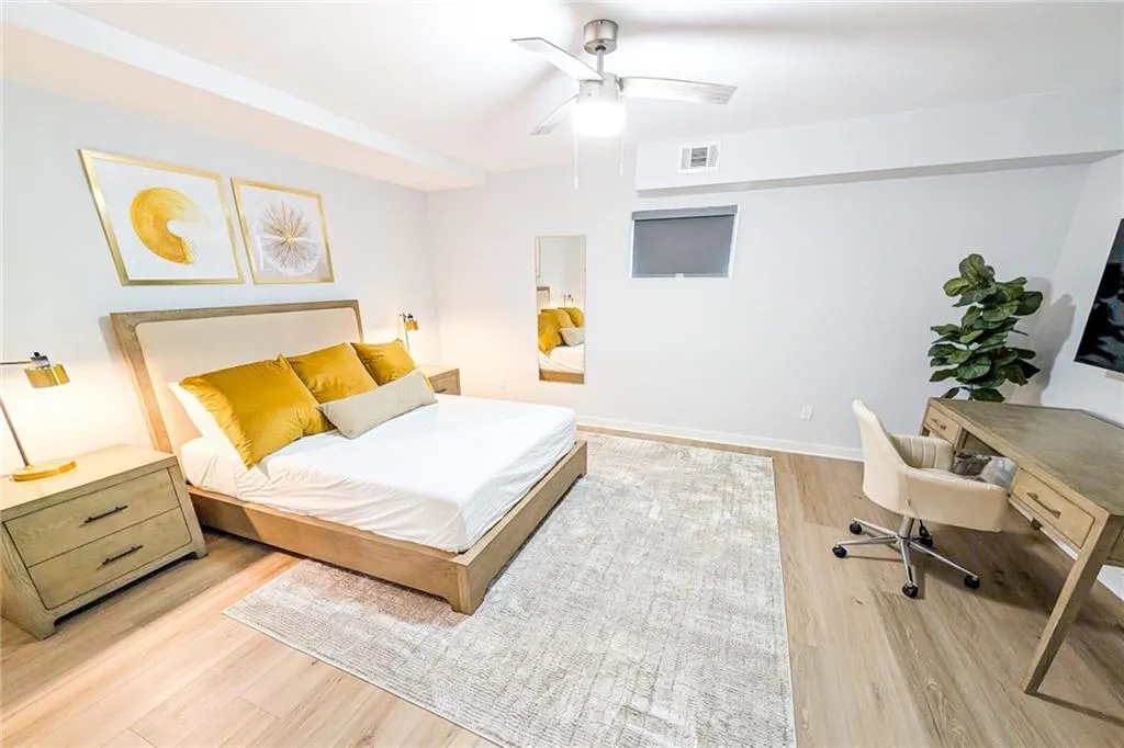 Bedroom featuring an office area, light wood-style floors, and a ceiling fan