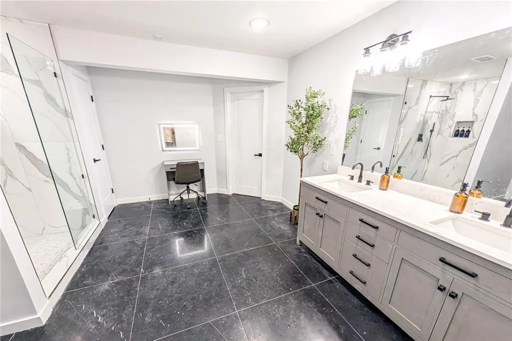 Full bath with a marble finish shower and double vanity