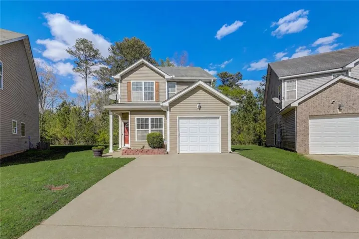Siding exterior with a covered porch entry, attached garage, concrete driveway, and front lawn