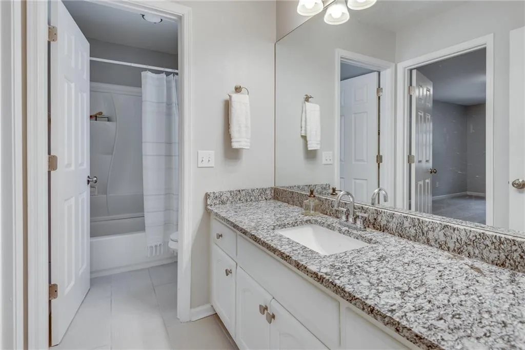 Full bathroom with tile patterned flooring, shower / bath combo with shower curtain, toilet, and vanity