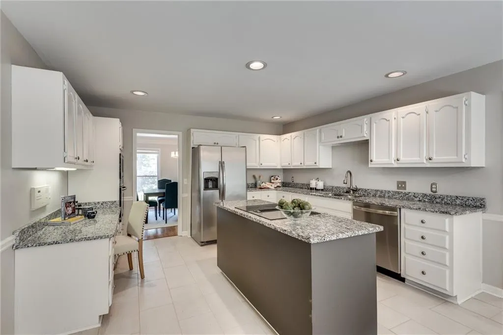 Kitchen with light tile patterned flooring, a center island, white cabinets, and stainless steel appliances