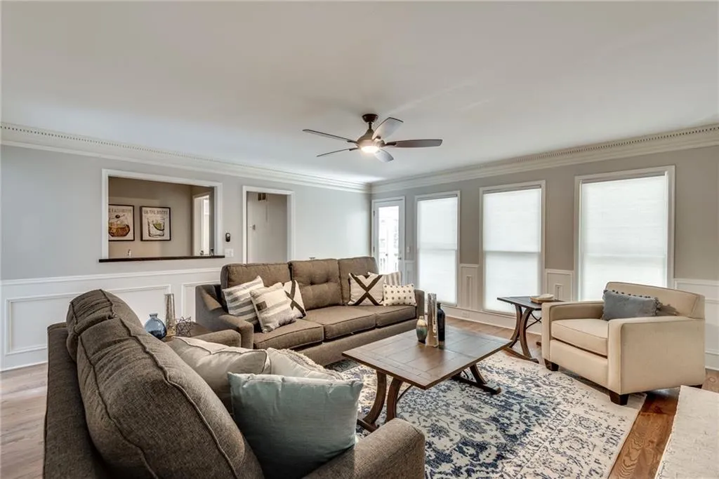 Living room with hardwood / wood-style flooring, crown molding, and ceiling fan