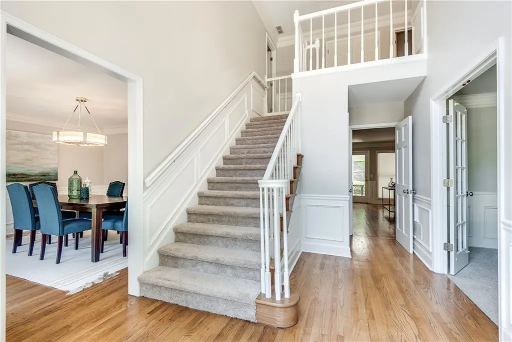 Staircase featuring light hardwood / wood-style floors, ornamental molding, and an inviting chandelier