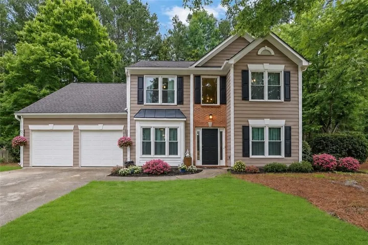 Two-story residence featuring light brown siding and dark shutters