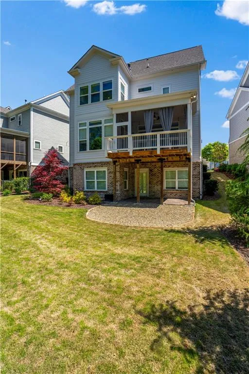 Rear view of property featuring brick siding, a sunroom, a lawn, and a patio area