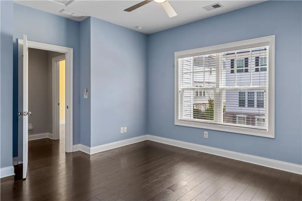 Unfurnished room featuring visible vents, baseboards, a ceiling fan, and dark wood-style floors