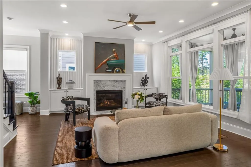 Living area featuring a high end fireplace, dark wood-type flooring, ornamental molding, and ceiling fan