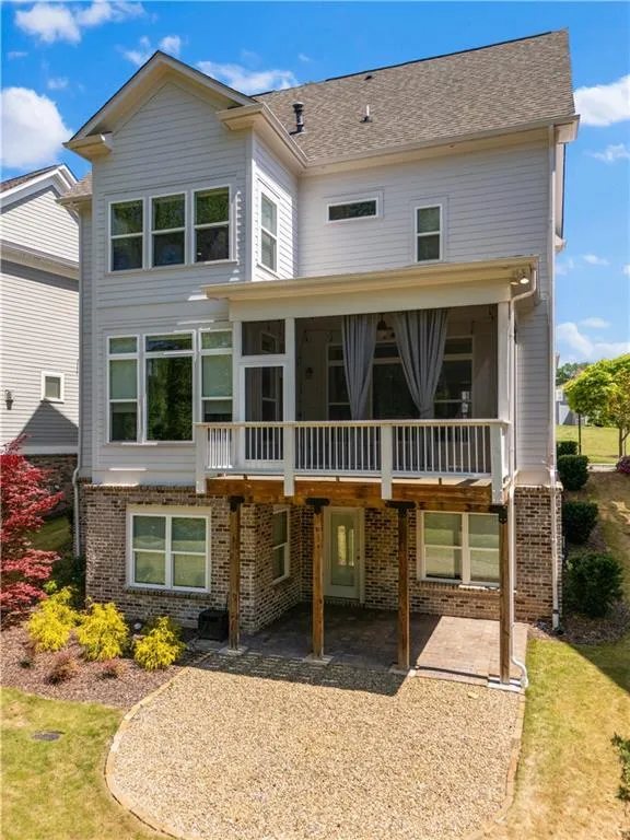 Back of property featuring roof with shingles, a patio, brick siding, and a sunroom
