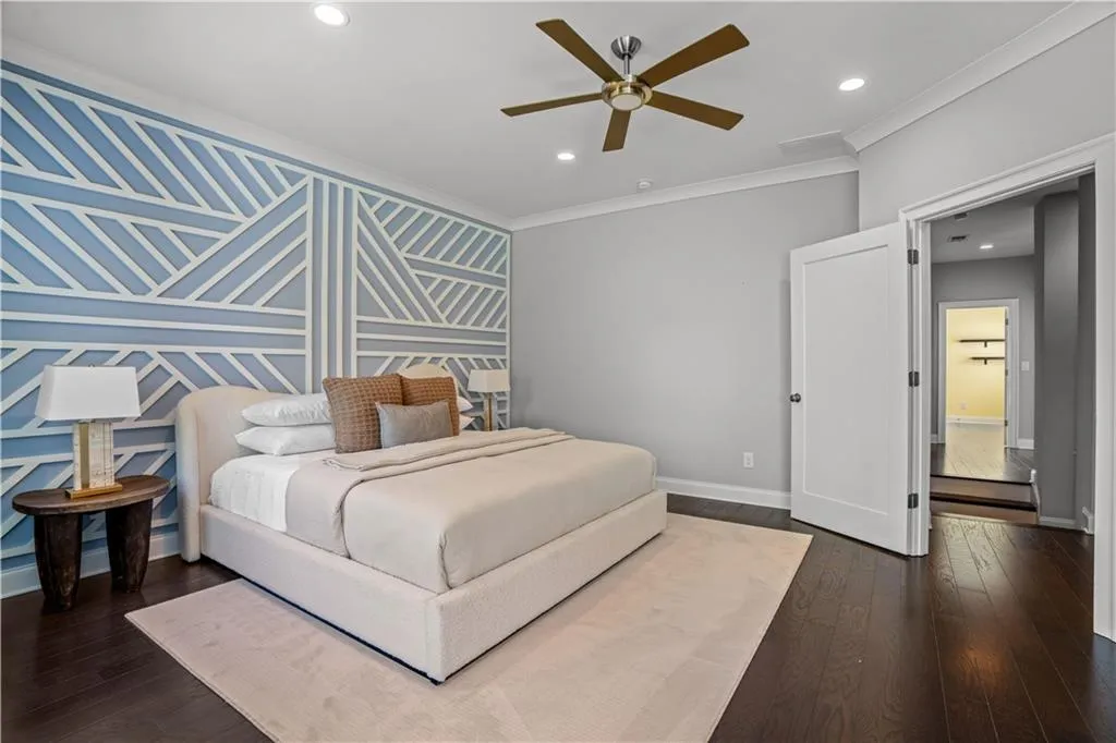 Bedroom with an accent wall, ornamental molding, recessed lighting, wood finished floors, and baseboards
