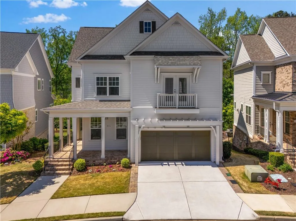 View of front of home featuring covered porch, a balcony, an attached garage, a shingled roof, and concrete driveway