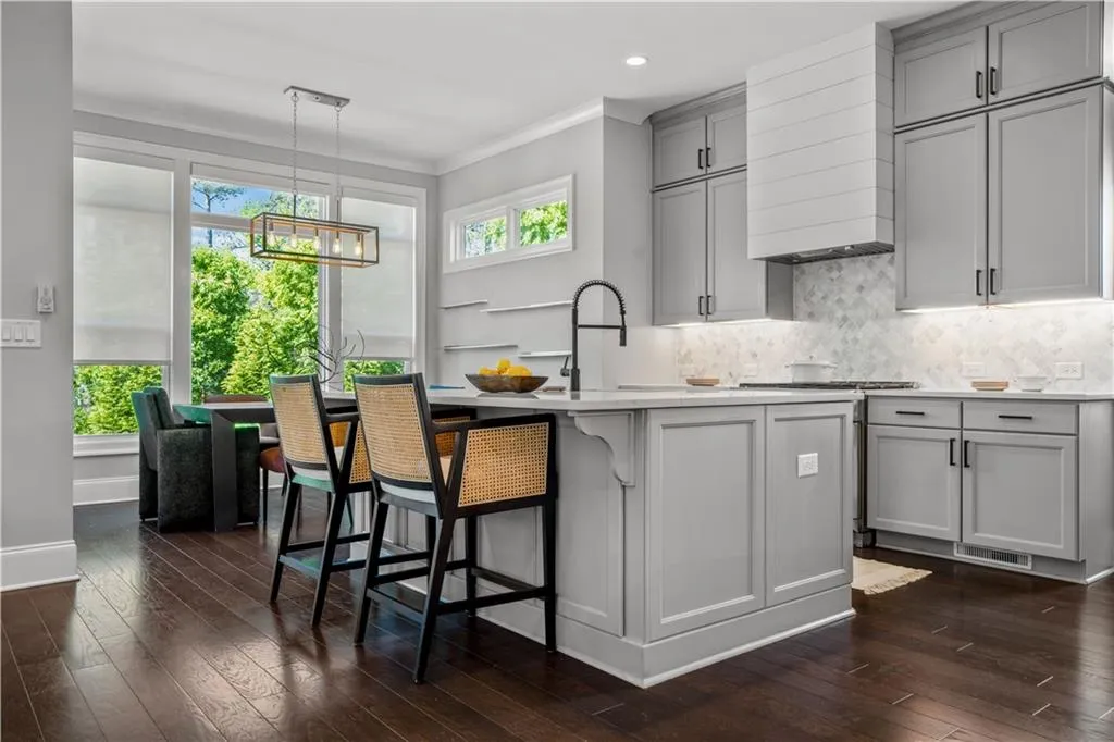 Kitchen featuring a sink, dark wood-style flooring, light countertops, gray cabinetry, and decorative backsplash