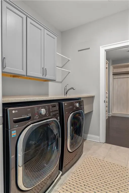 Laundry room with separate washer and dryer, baseboards, light tile patterned flooring, and cabinet space