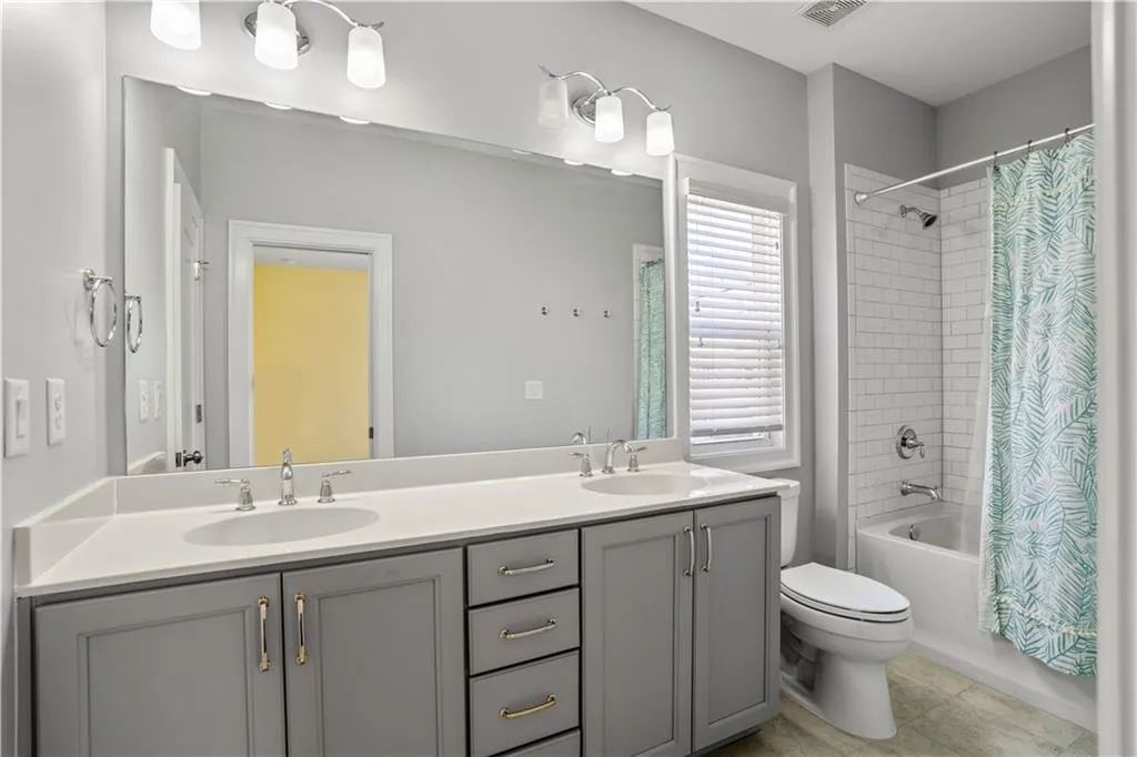 Full bathroom featuring shower / tub combo with curtain, double vanity, and a sink