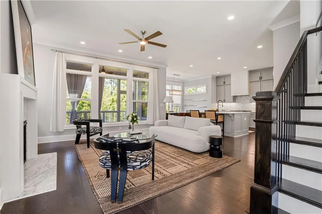 Living area featuring dark wood-style flooring, a ceiling fan, and a wealth of natural light