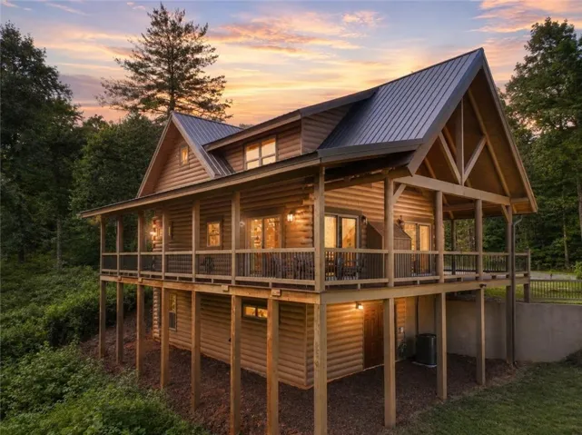 Log cabin construction featuring a metal roof and a full-length wrap-around porch
